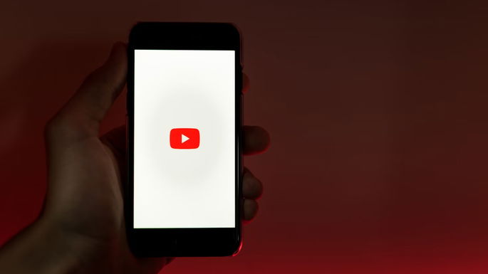 Homem a pegar num telemóvel e a abrir o YouTube